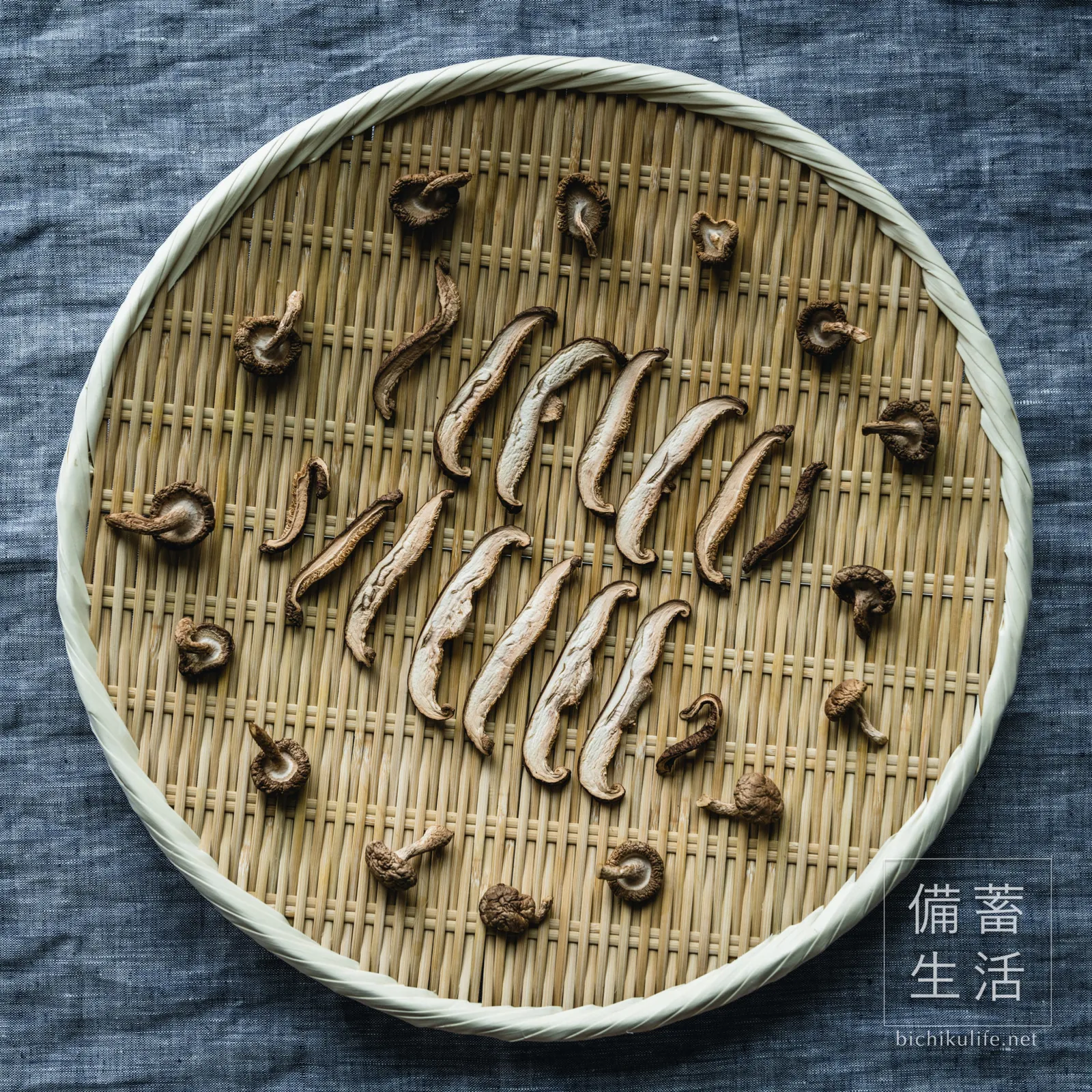 ざるの上で干し上がった丸ごとの干し椎茸と、薄切りにしたジャンボ椎茸