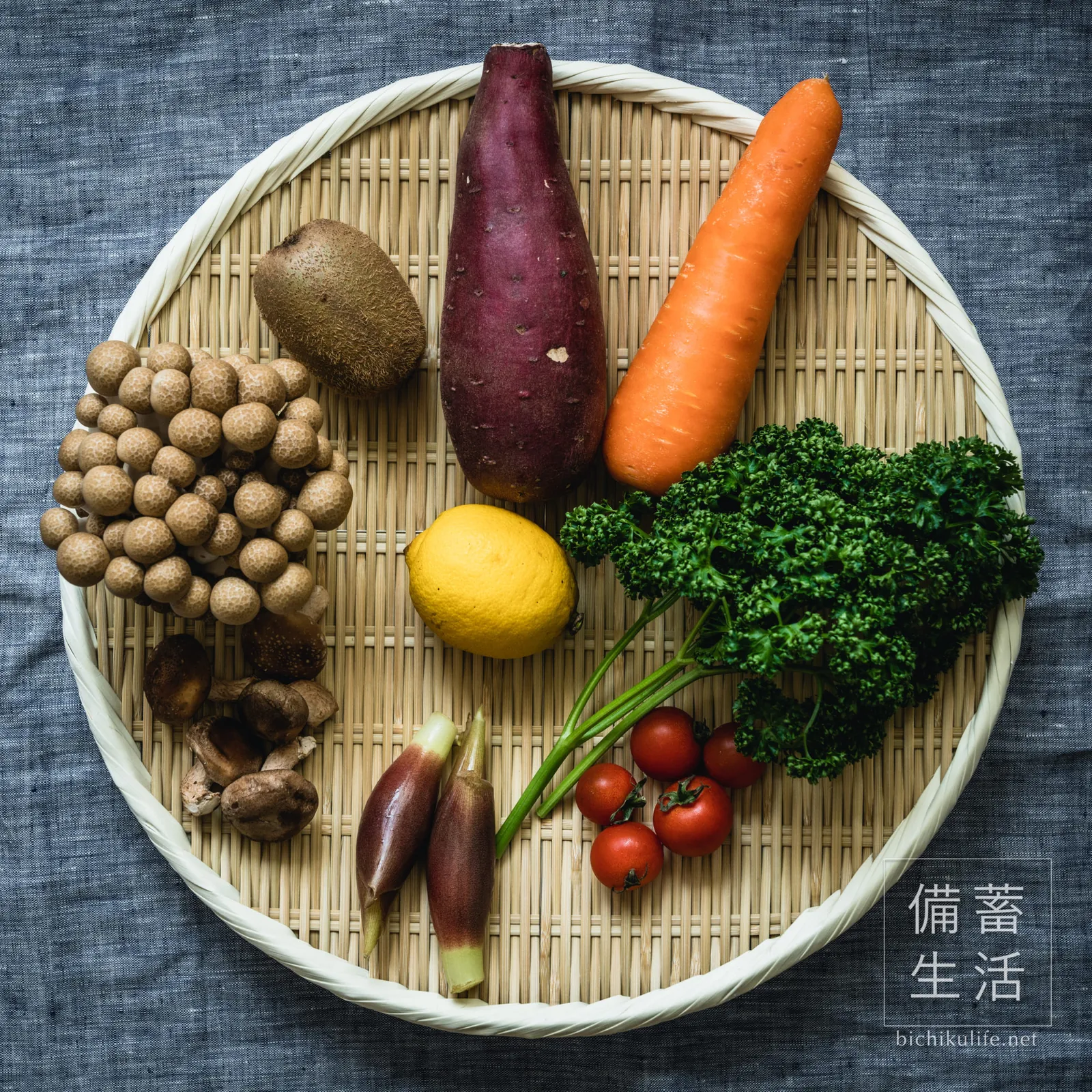 竹ざるにのせた人参、さつまいも、ミニトマト、レモン、しめじなどの野菜
