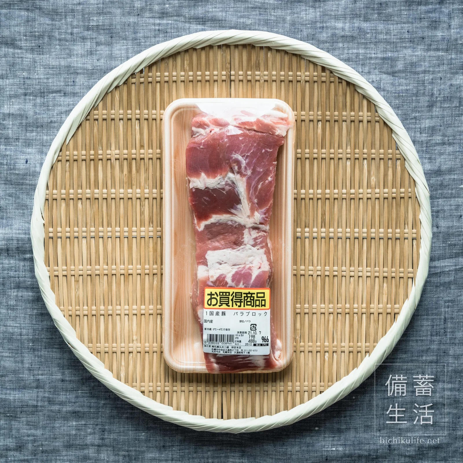 ざるにのせた、パック入りの豚バラ肉のかたまり